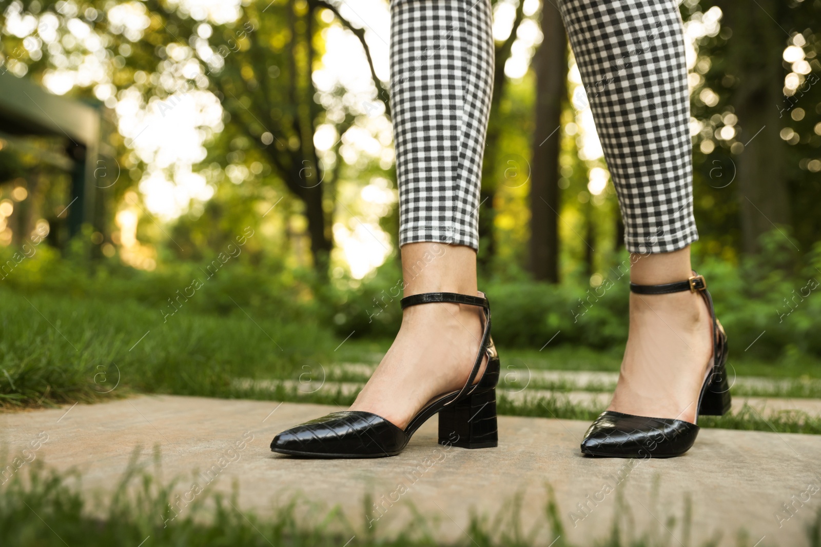 Photo of Woman in stylish black shoes walking at park, closeup