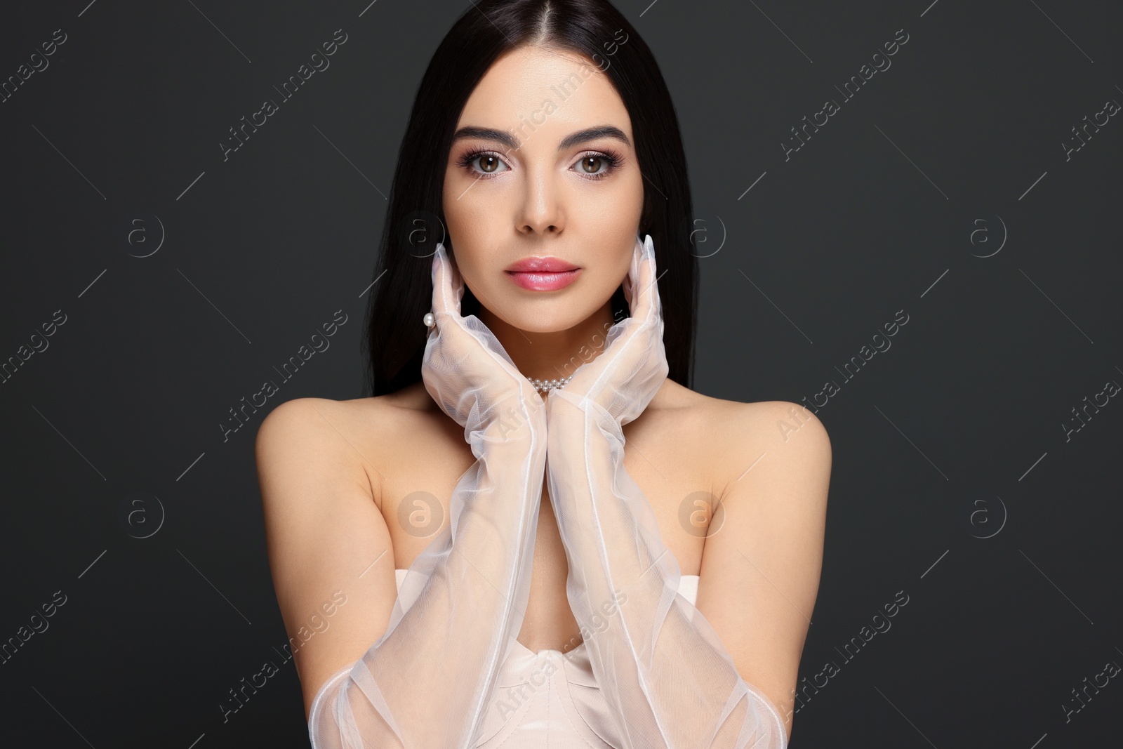 Photo of Portrait of beautiful young woman in evening gloves on black background