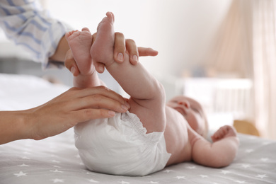 Photo of Mother changing her baby's diaper on bed