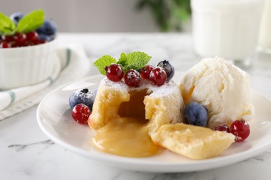 Tasty vanilla fondant with white chocolate, berries and ice cream on white marble table, closeup