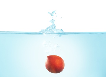 Photo of Peach falling down into clear water against white background