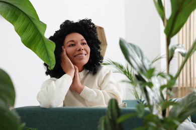 Photo of Relaxing atmosphere. Happy woman surrounded by beautiful houseplants indoors