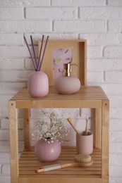 Shelving unit with toiletries near white brick wall indoors. Bathroom interior element