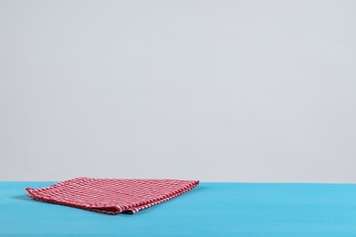 Photo of Napkin on light blue wooden table against white background. Space for text