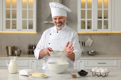 Photo of Professional chef making dough at white marble table in kitchen