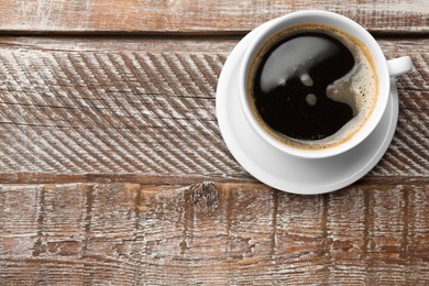 Cup of aromatic coffee on wooden table, top view. Space for text