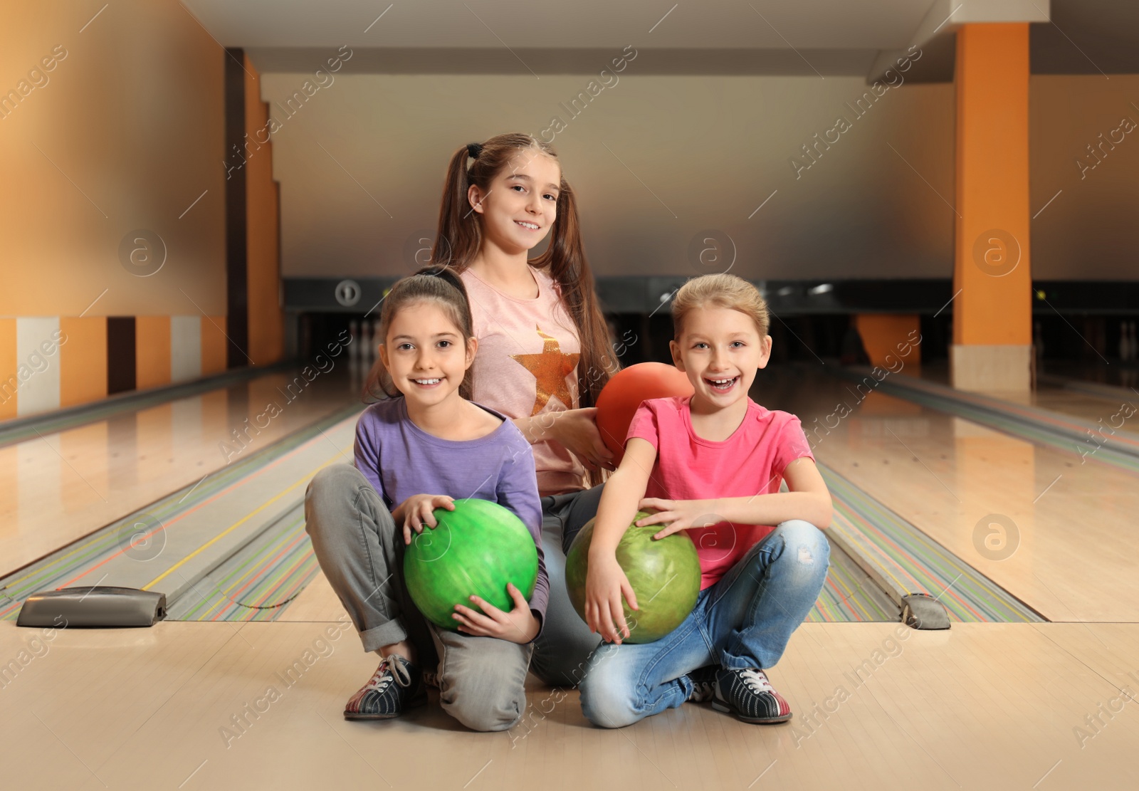 Photo of Happy girls with balls in bowling club