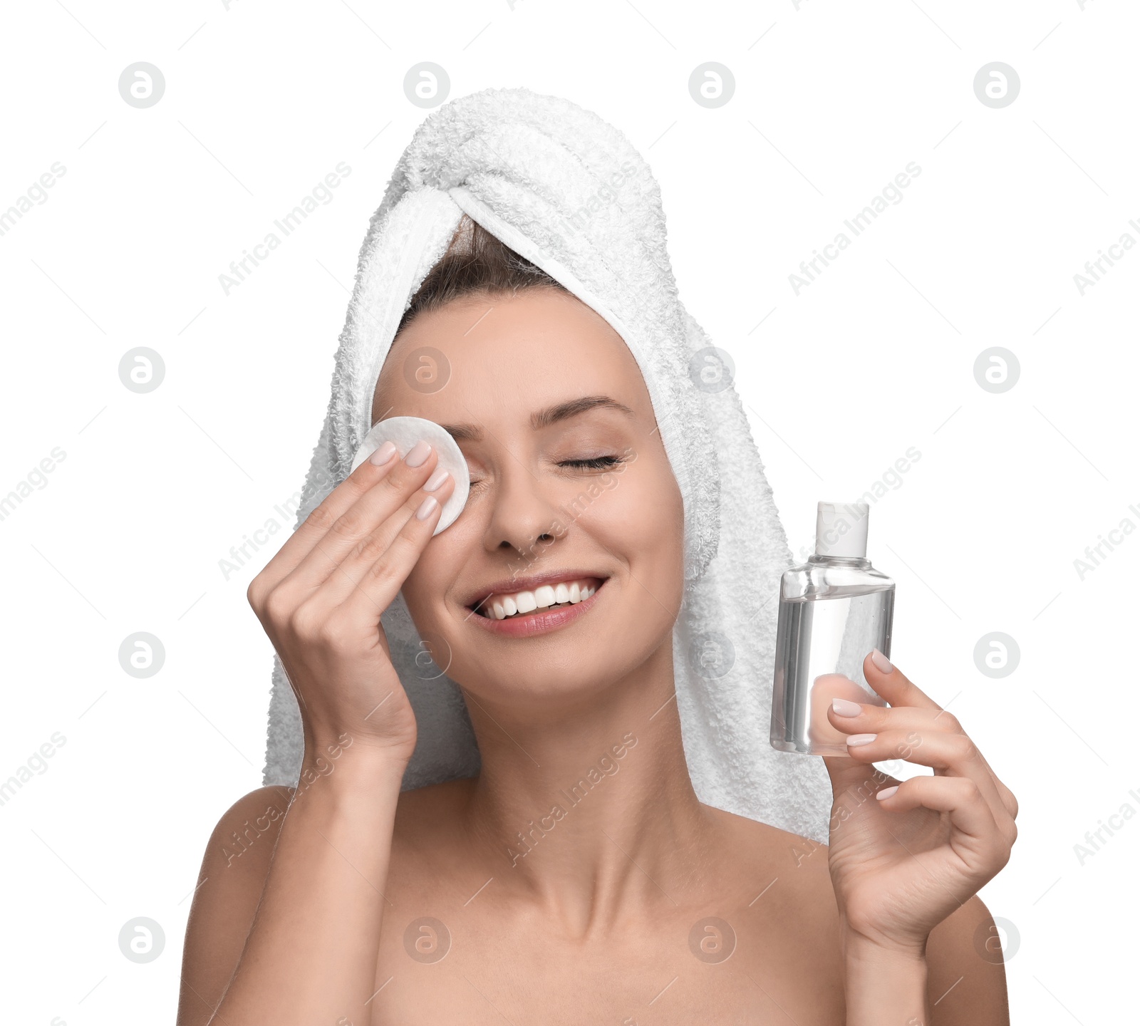 Photo of Smiling woman removing makeup with cotton pad and holding bottle on white background