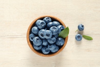 Photo of Bowl of fresh tasty blueberries on white wooden table, flat lay