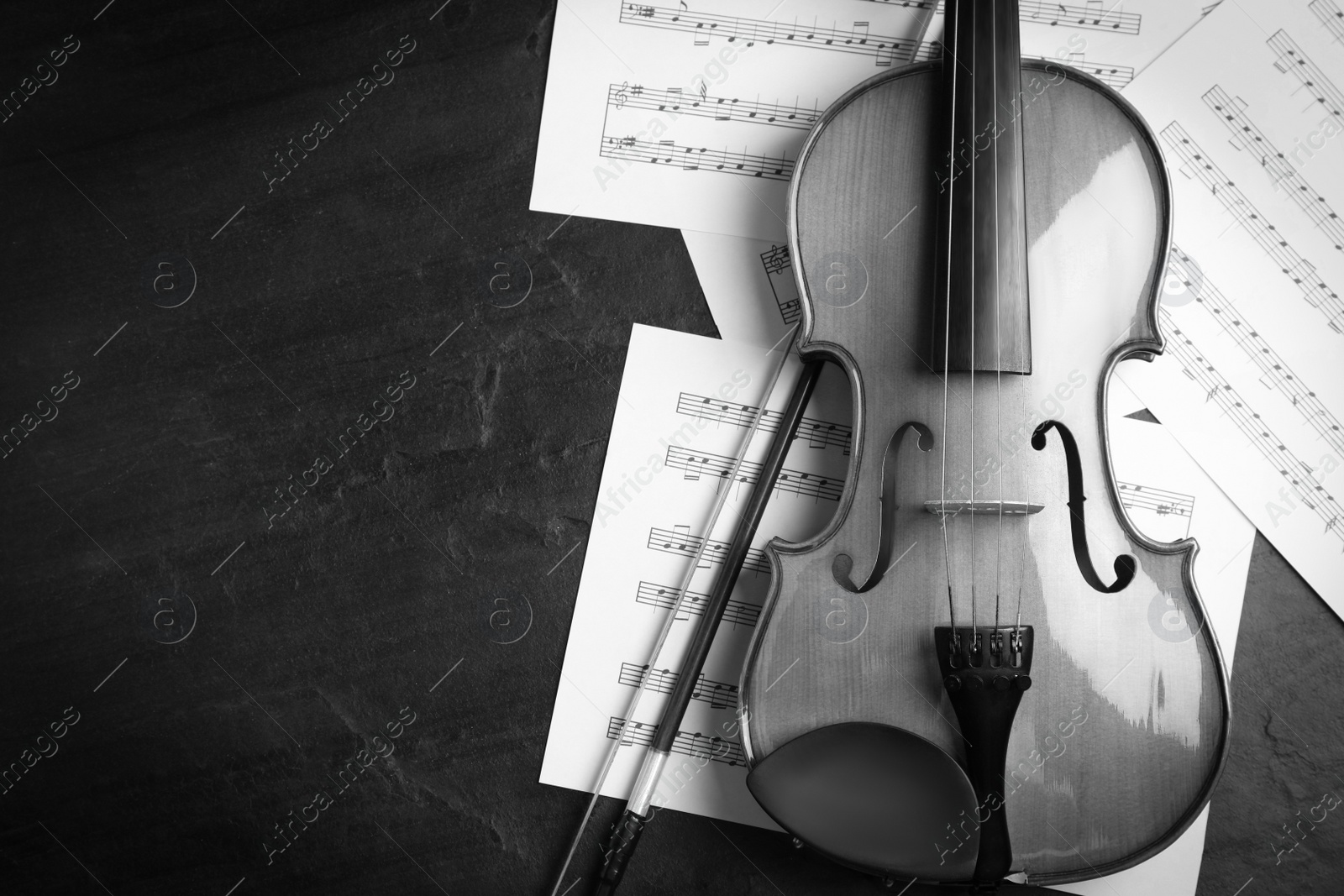 Image of Violin, bow and note sheets on wooden table, flat lay with space for text. Black and white tone 