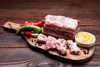 Photo of Pieces of pork fatback with chilli pepper and sauce on wooden table
