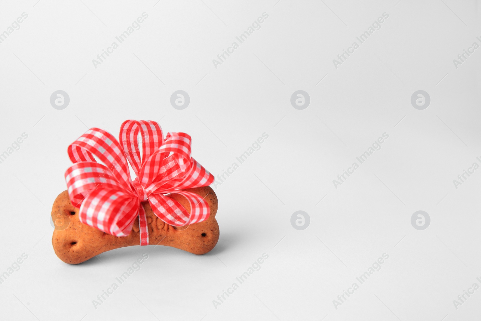 Photo of Bone shaped dog cookie with bow on white background. Space for text