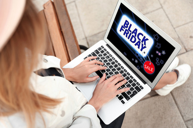 Image of Black Friday. Woman shopping online using laptop outdoors, closeup