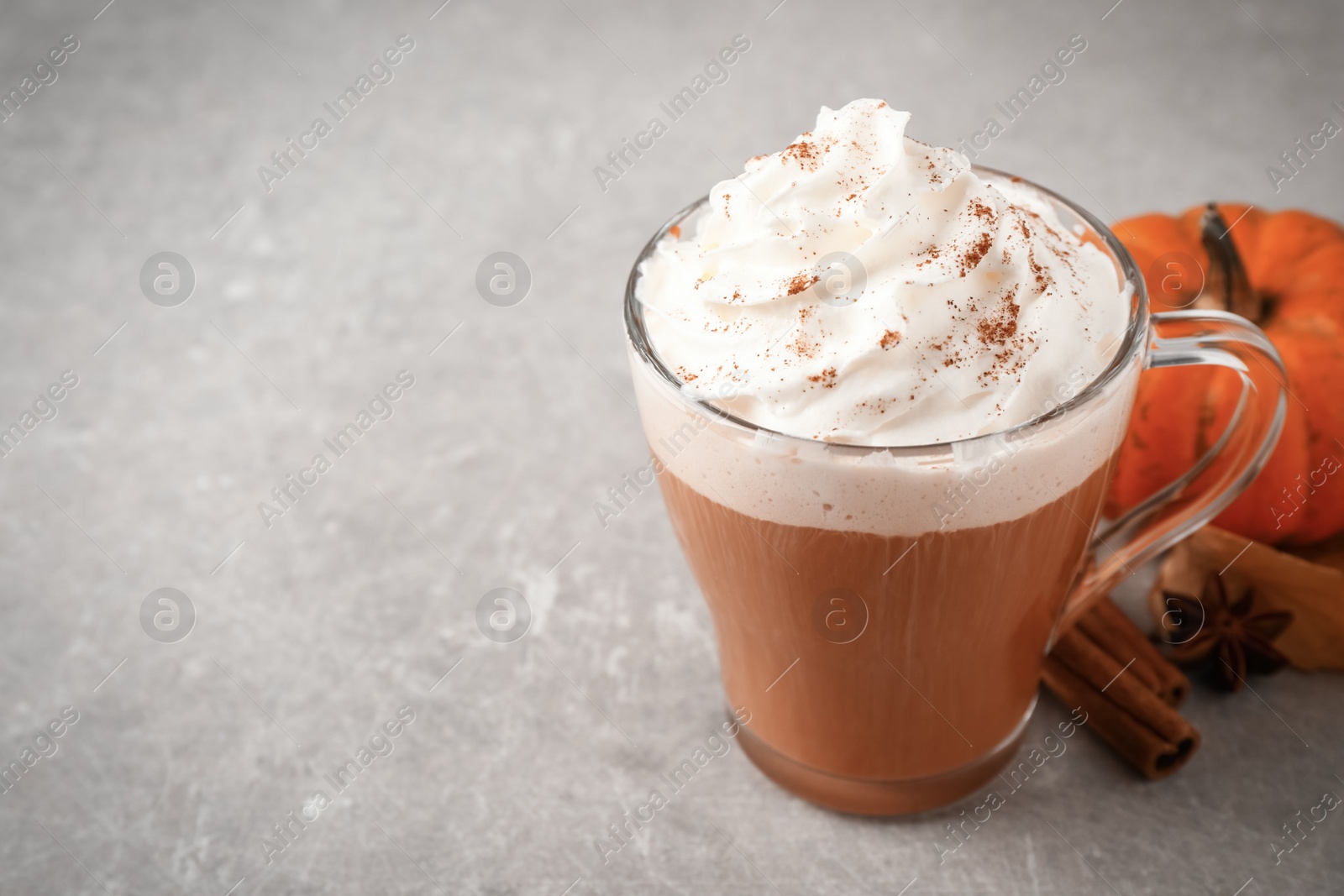 Photo of Delicious pumpkin latte on grey table, closeup. Space for text