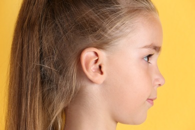 Photo of Cute little girl on color background, closeup. Hearing problem