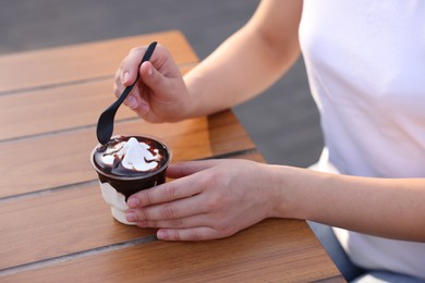 Photo of Lviv, Ukraine - September 26, 2023: Woman with McDonald's ice cream at wooden table outdoors, closeup