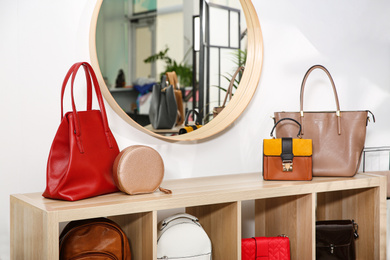 Photo of Collection of stylish woman's bags on wooden shelving unit indoors