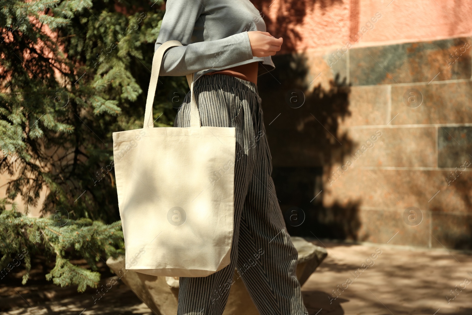 Photo of Young woman with cotton bag on city street, closeup. Mockup for design