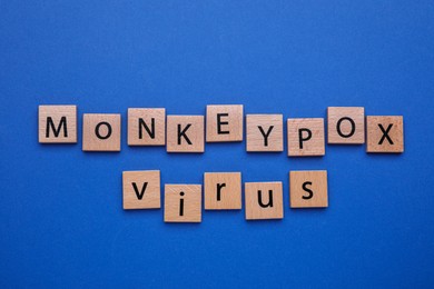 Words Monkeypox Virus made of wooden squares on blue background, flat lay