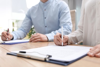 Photo of Woman signing contract at table in office, closeup.