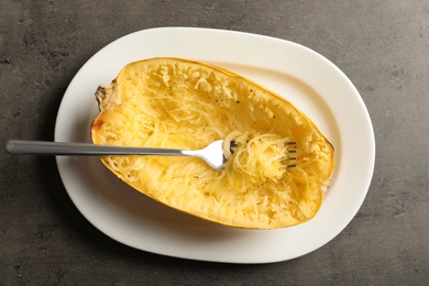 Photo of Plate with cooked spaghetti squash and fork on gray background