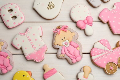Photo of Cute tasty cookies of different shapes on white wooden table, flat lay. Baby shower party