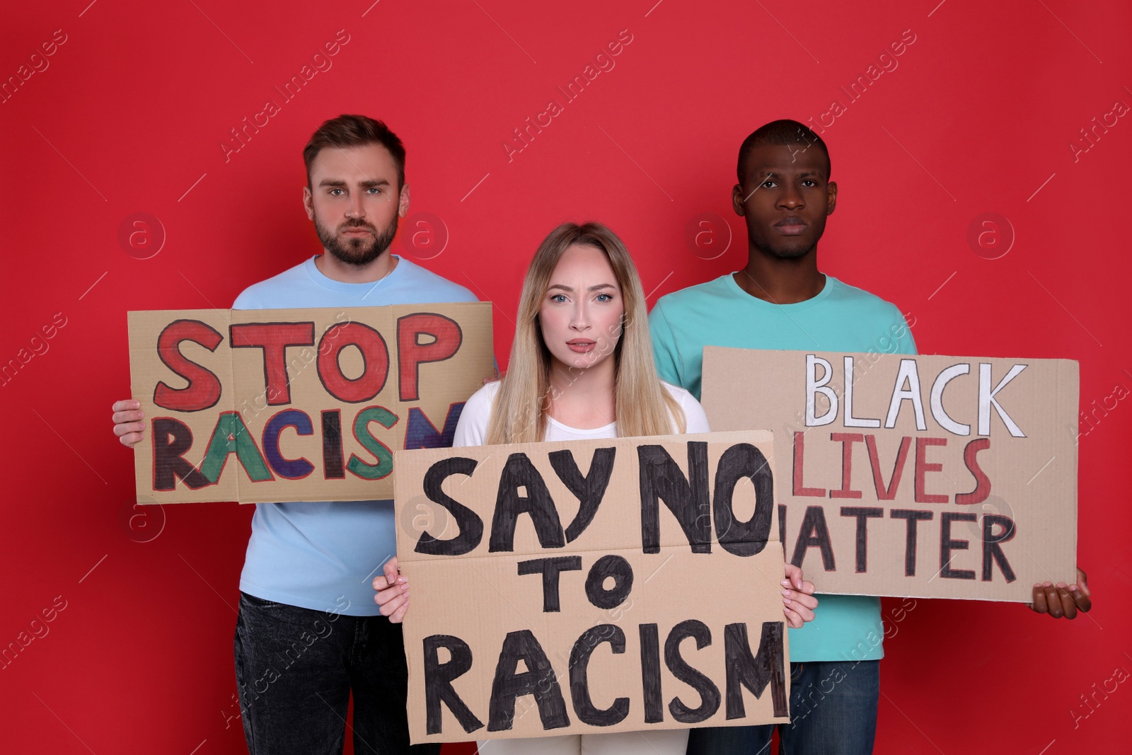 Photo of Protesters demonstrating different anti racism slogans on red background. People holding signs with phrases