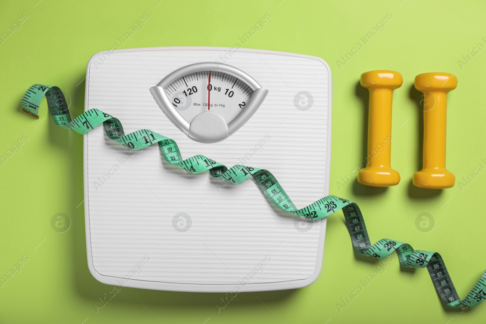 Photo of Weight loss concept. Scales, dumbbells and measuring tape on green background, flat lay