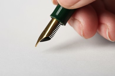 Photo of Woman with fountain pen above light paper, closeup. Space for text