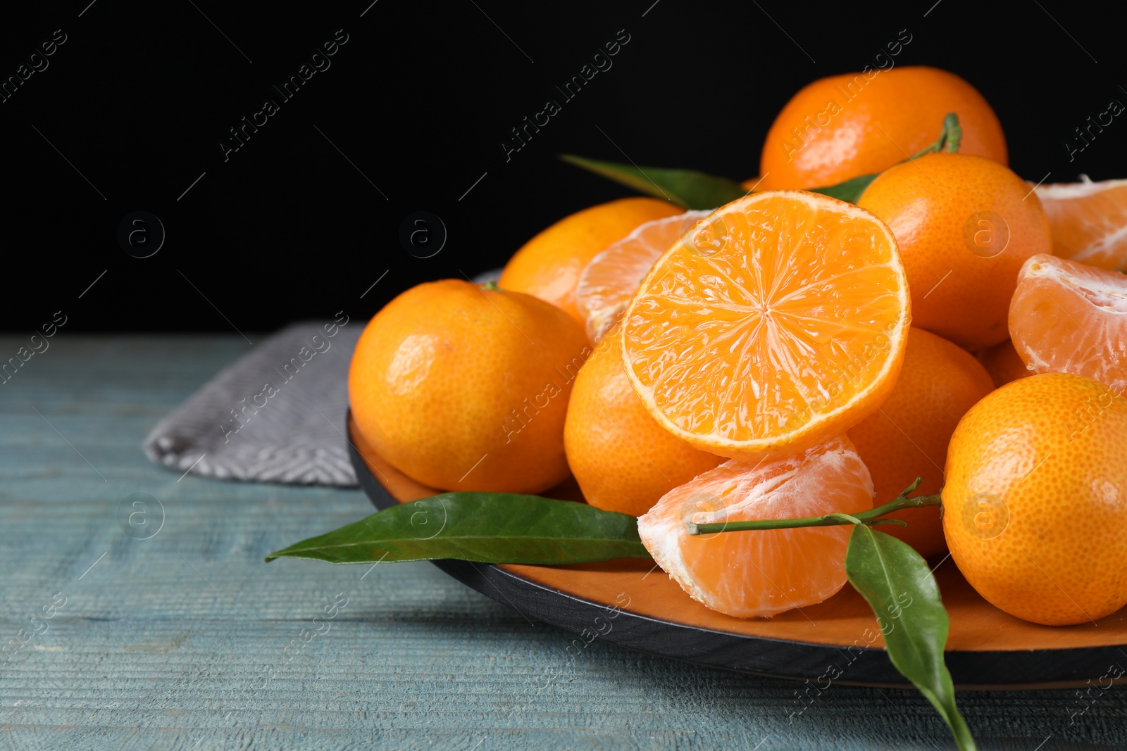 Photo of Fresh ripe tangerines on blue wooden table, closeup