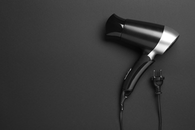 Photo of Hair dryer on black background, top view with space for text. Professional hairdresser tool