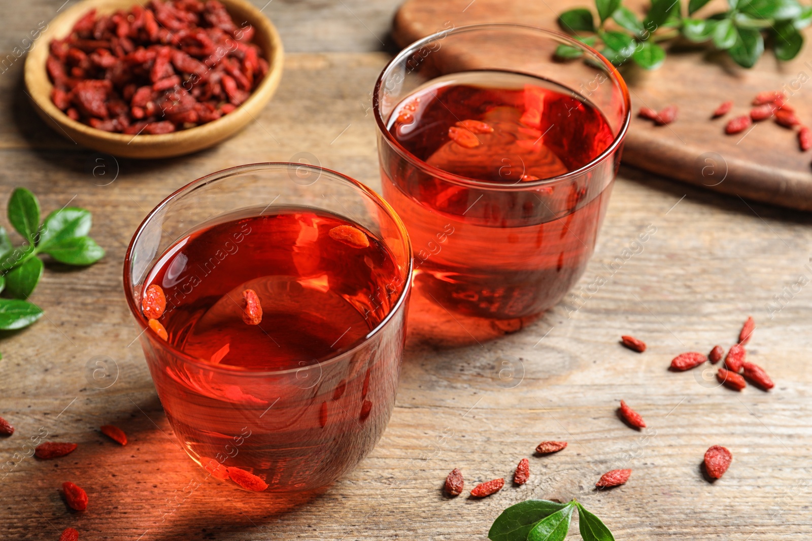 Photo of Healthy goji juice in glasses on wooden table