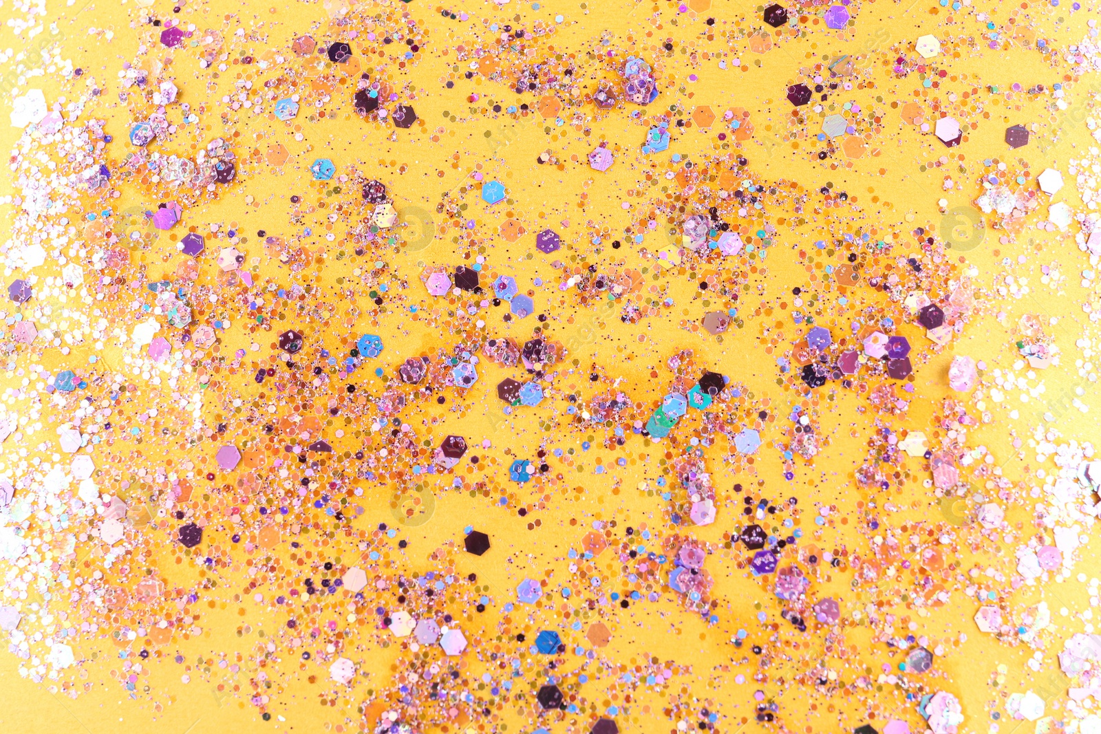 Photo of Shiny glitter on yellow background, top view