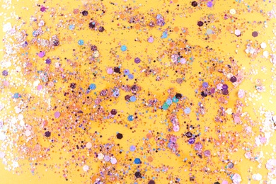 Photo of Shiny glitter on yellow background, top view