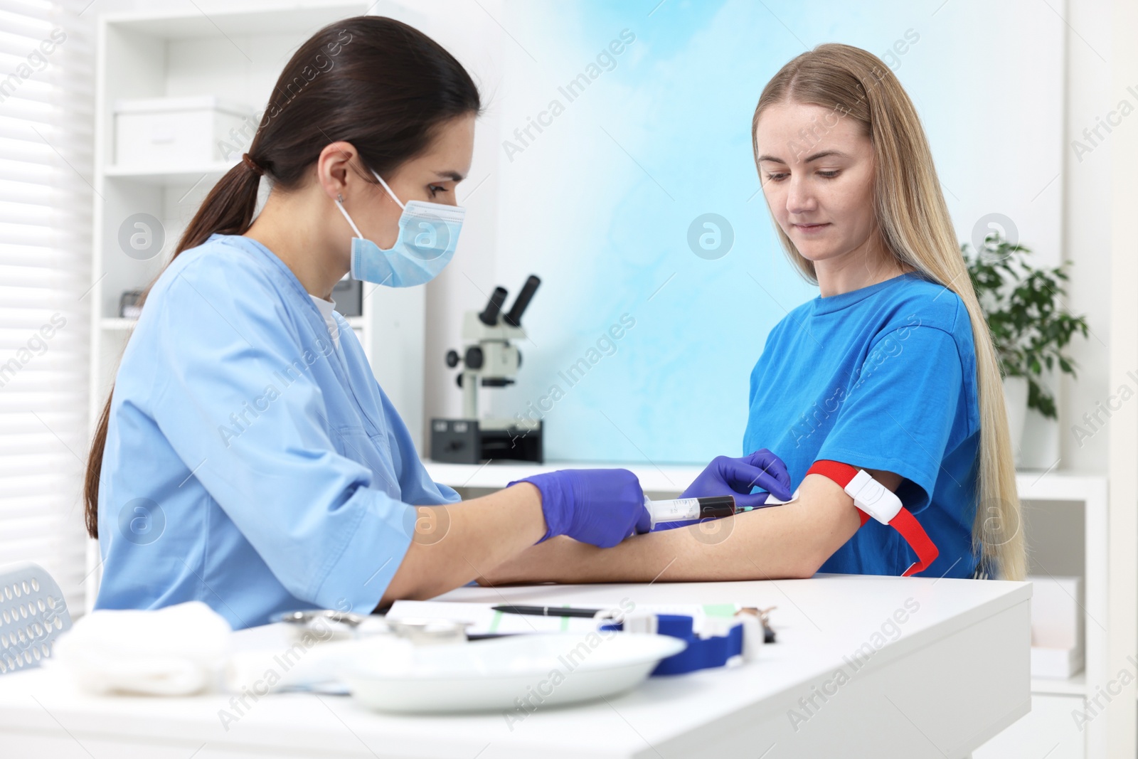 Photo of Laboratory testing. Doctor taking blood sample from patient at white table in hospital