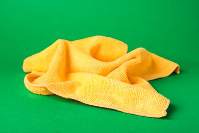 Orange microfiber cloth on green background, closeup