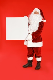 Photo of Authentic Santa Claus with blank banner on red background. Space for design
