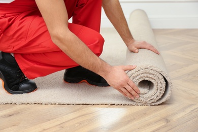 Worker rolling out new carpet flooring indoors, closeup