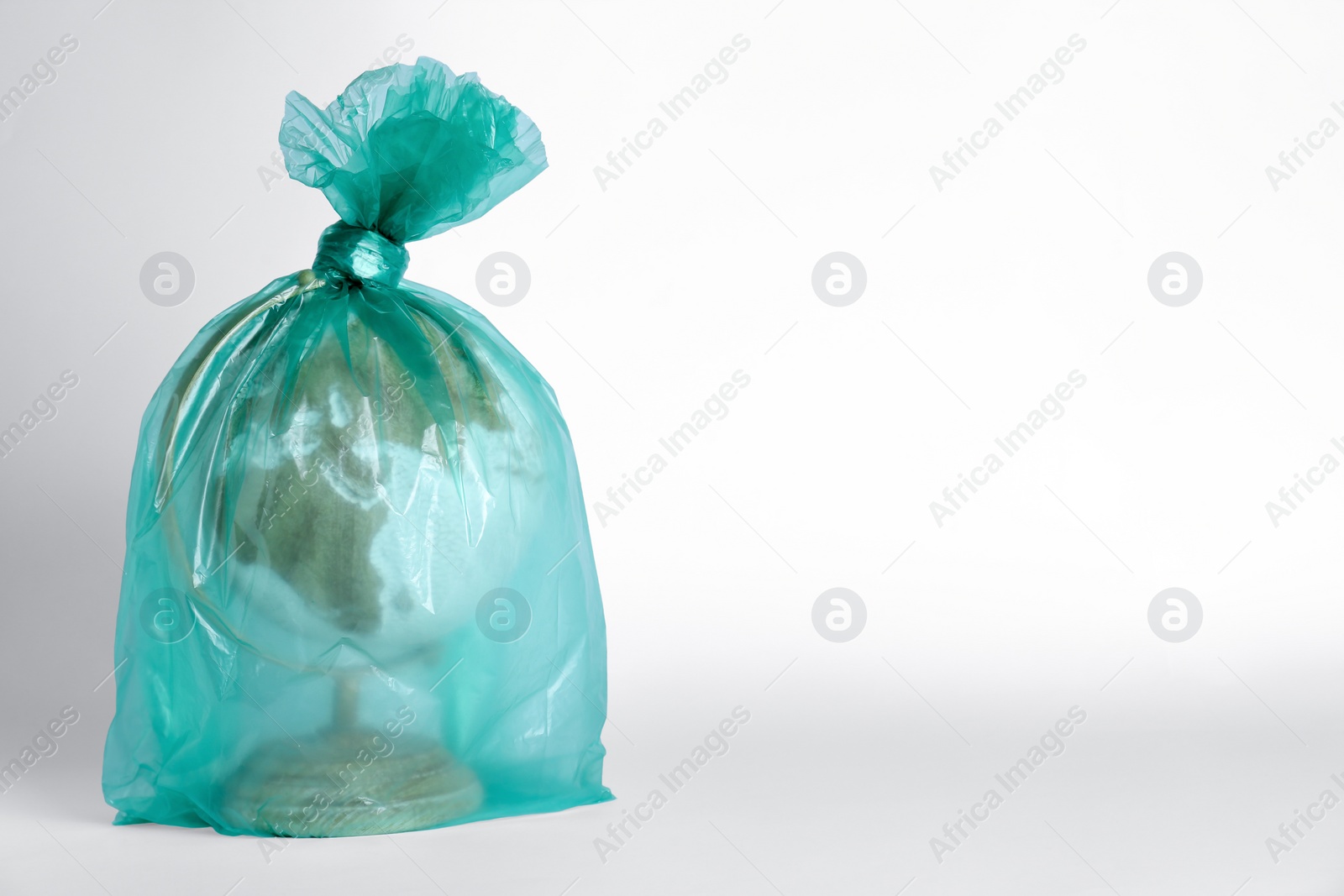 Photo of Globe in plastic bag on white background, space for text. Environmental conservation