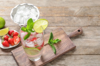 Glass of natural lemonade with lime, strawberries and mint on table