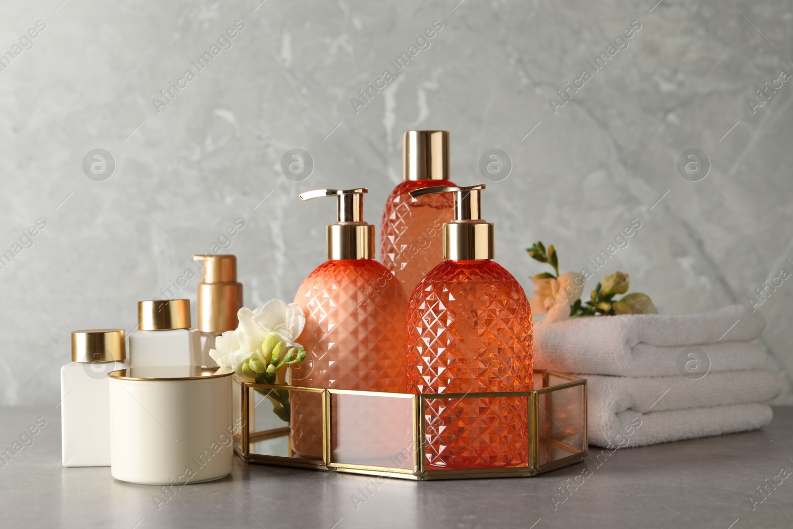 Photo of Stylish dispensers with liquid soap and other bathroom amenities on grey table