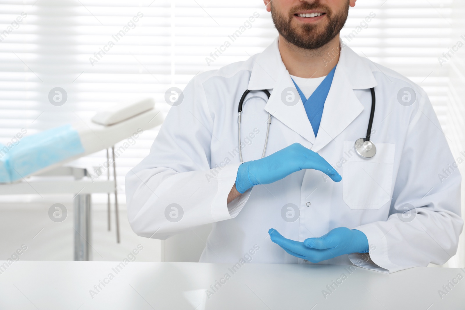 Photo of Young doctor holding something at table in clinic, closeup