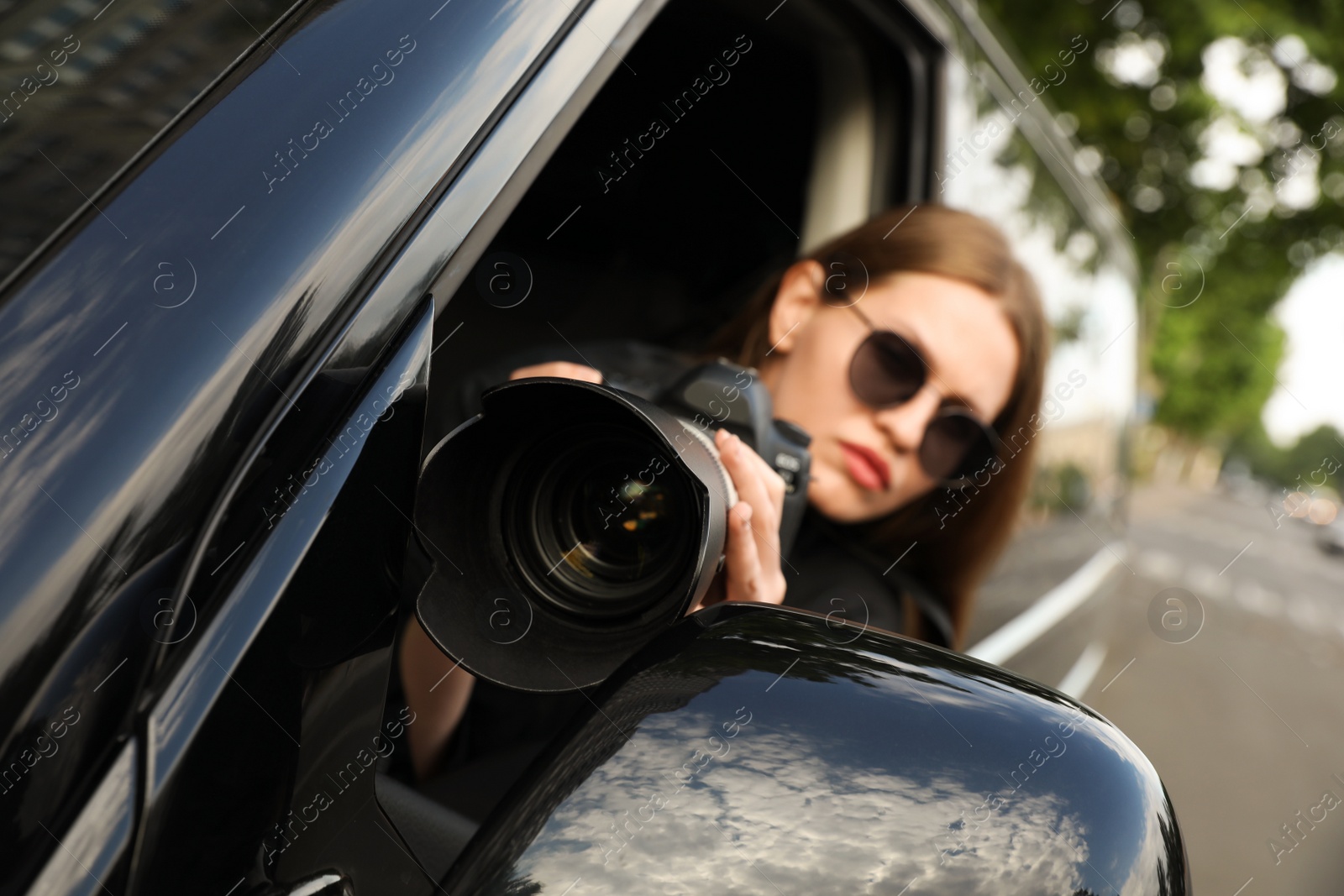 Photo of Private detective with modern camera spying from car, focus on lens