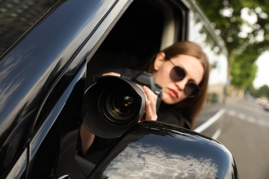 Photo of Private detective with modern camera spying from car, focus on lens