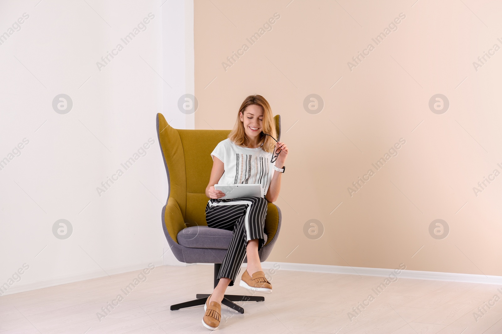 Photo of Young woman with tablet sitting in armchair at home. Space for text