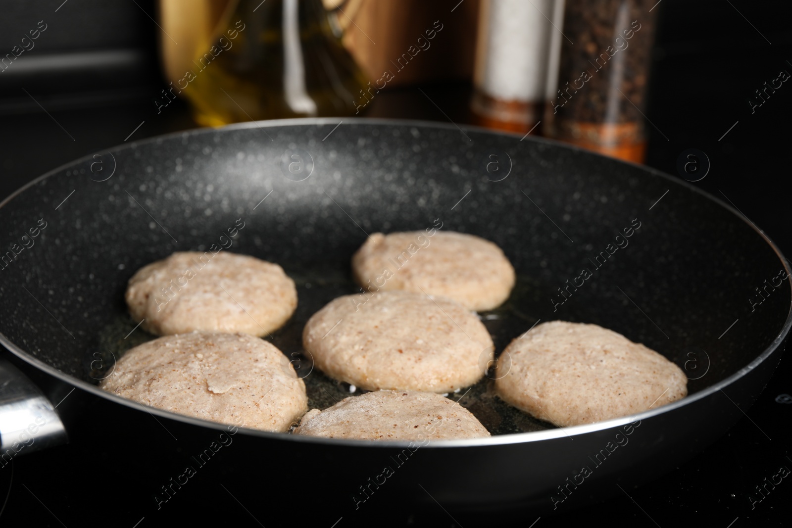 Photo of Cooking vegan nuggets in frying pan on cooktop, closeup