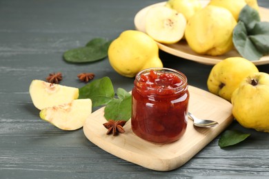 Photo of Delicious quince jam and fruits on grey wooden table