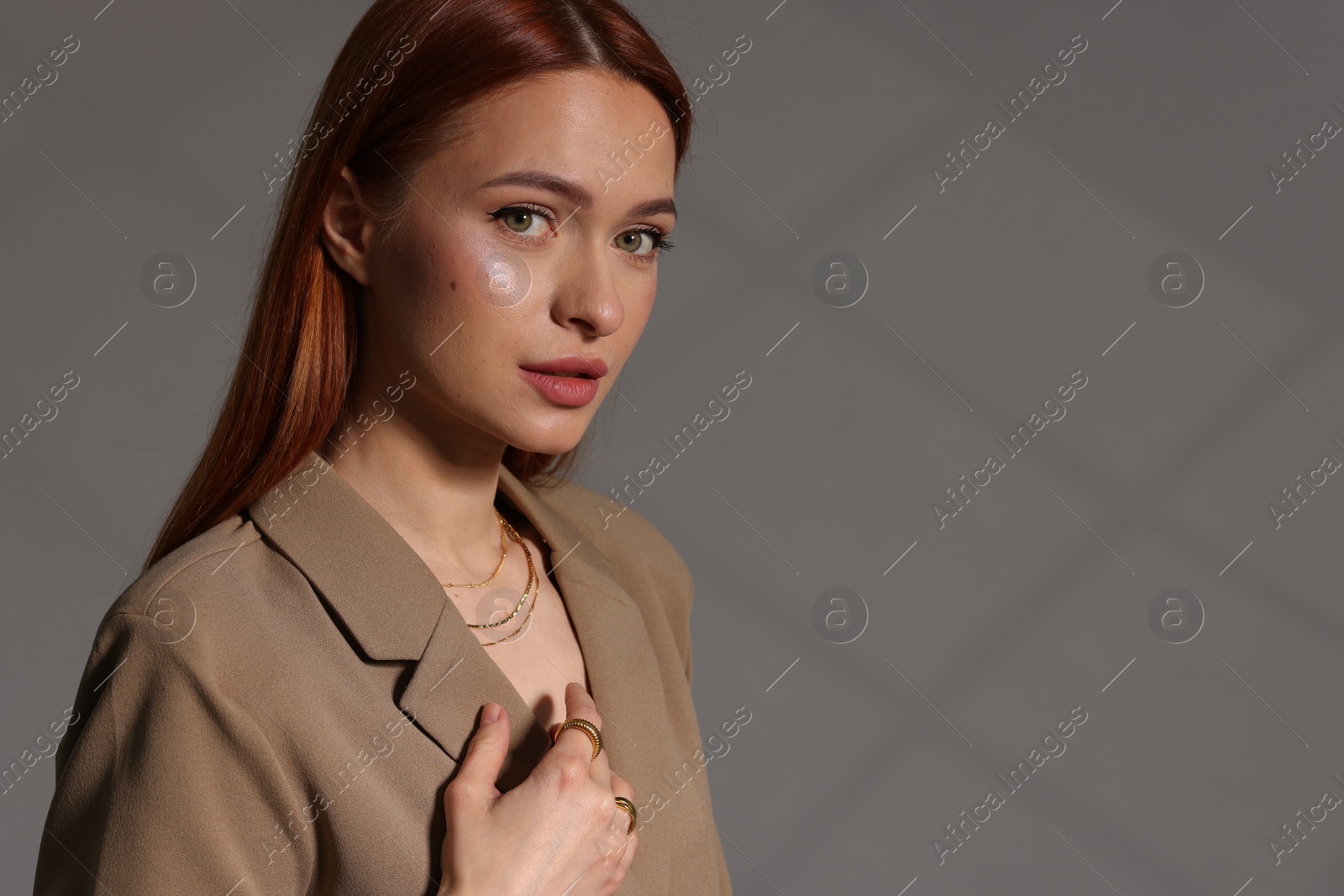 Photo of Beautiful young woman with elegant jewelry on gray background, space for text