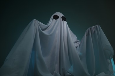 Creepy ghost. Woman covered with sheet on dark teal background