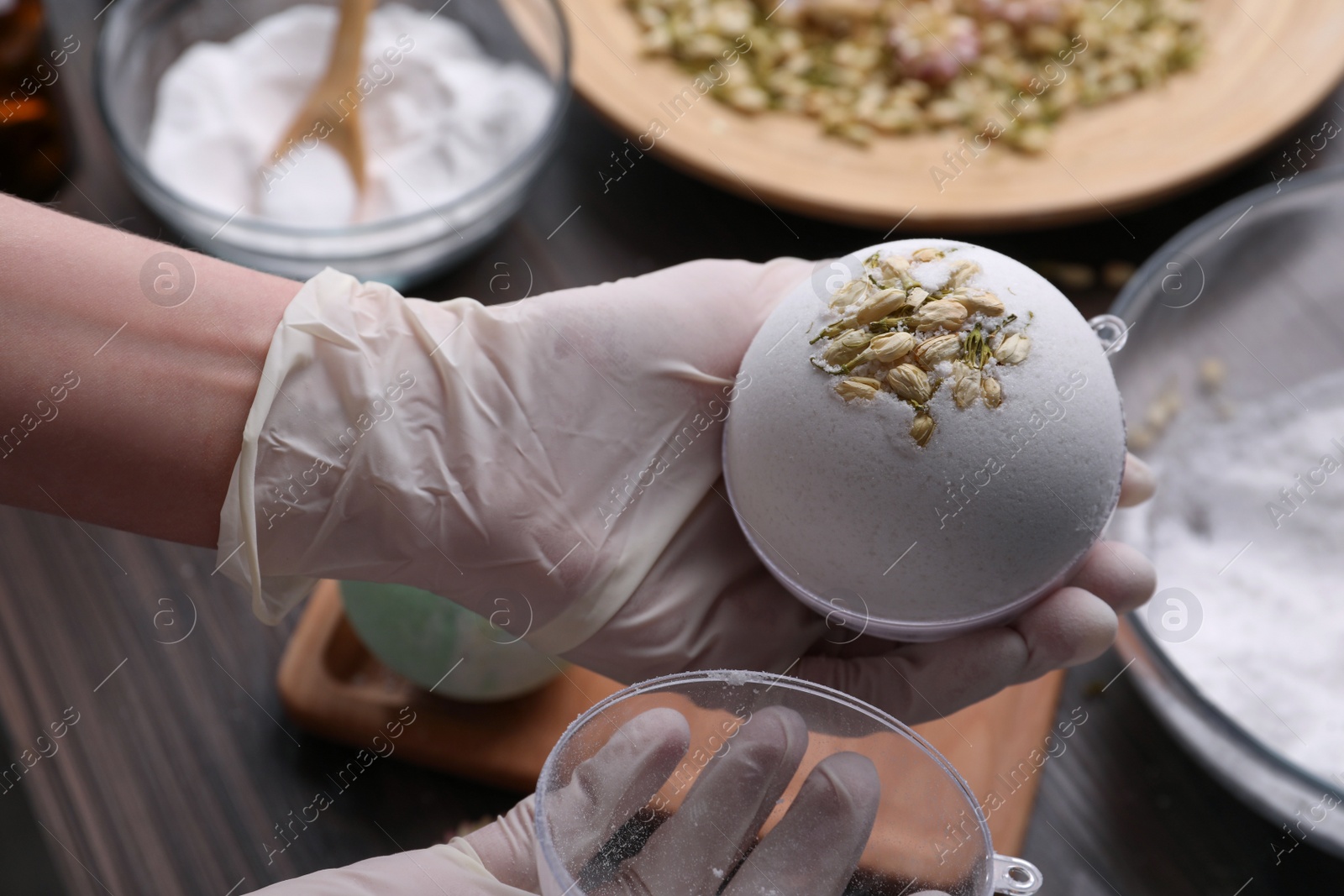 Photo of Woman in gloves making bath bomb at table, closeup